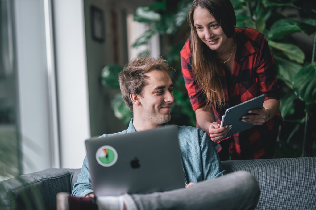 Two employees having a discussion and taking notes on their devices