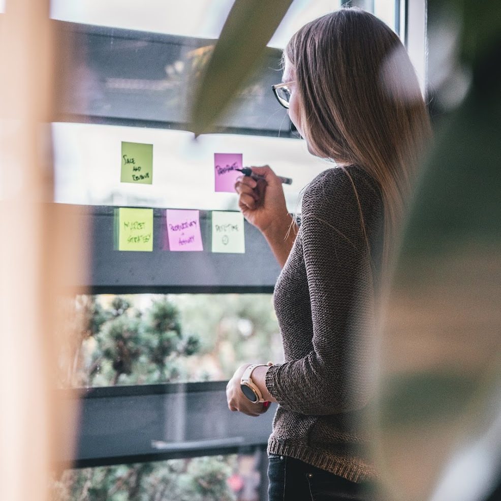 A woman is writing down ideas on colorful sticky notes