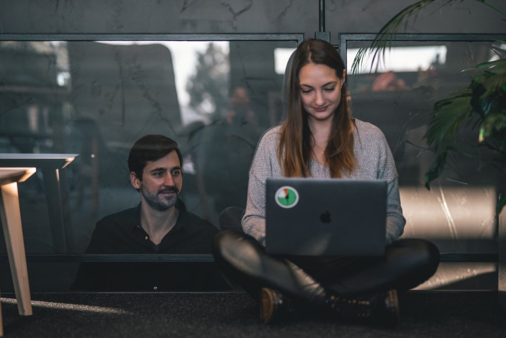 Two coworkers in the office dealing with difficult clients by setting boundaries in working hours and communication channels