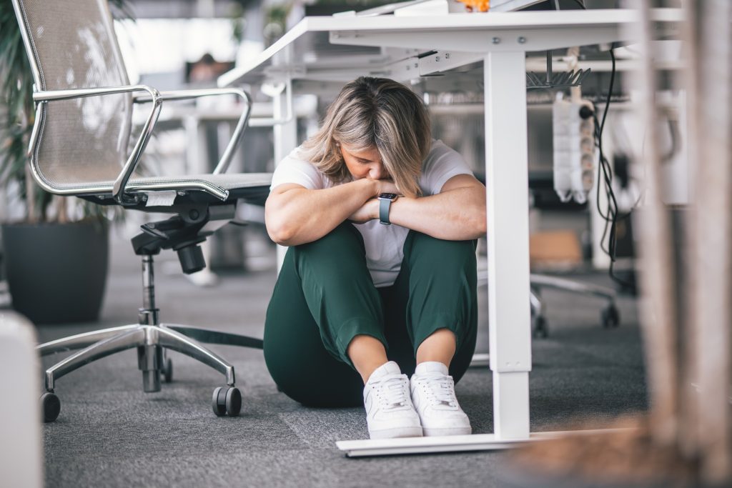 A woman hiding under the table in an office