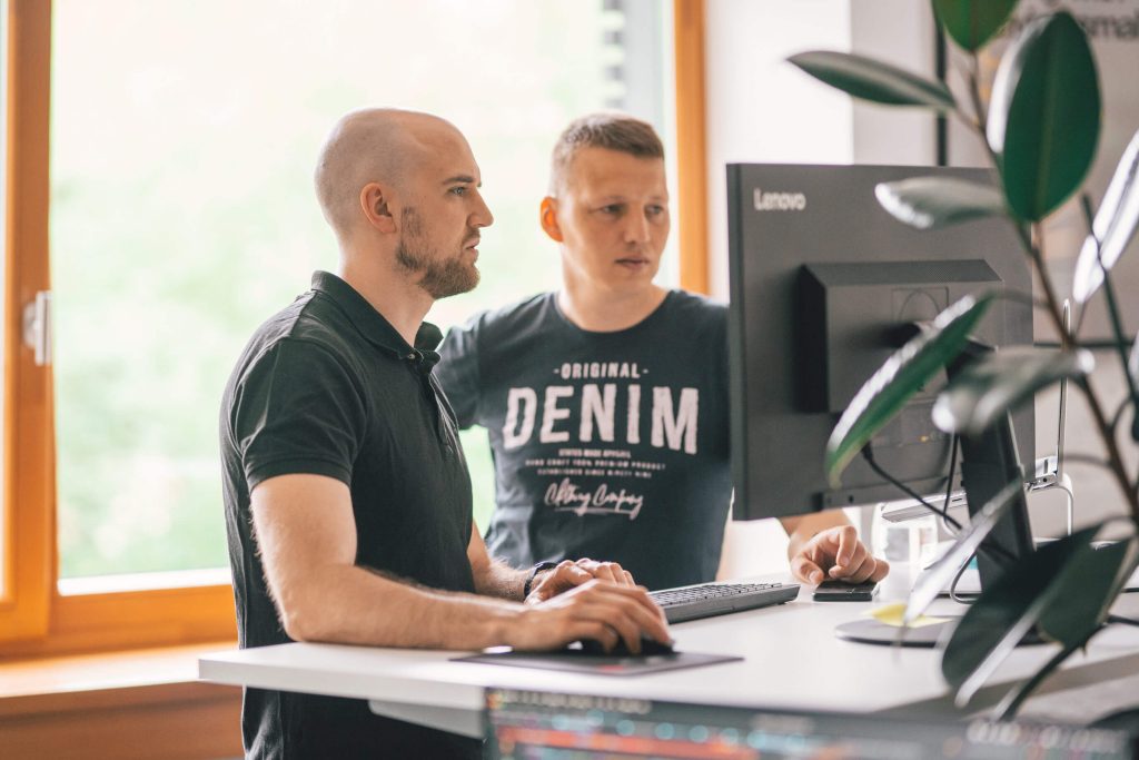 Team members working in front of a desk and looking at a computer screen