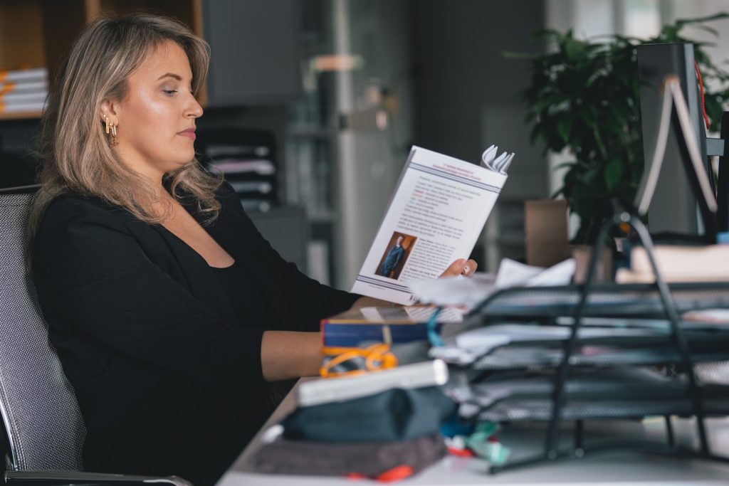 a woman reading a book at hear desk in the office