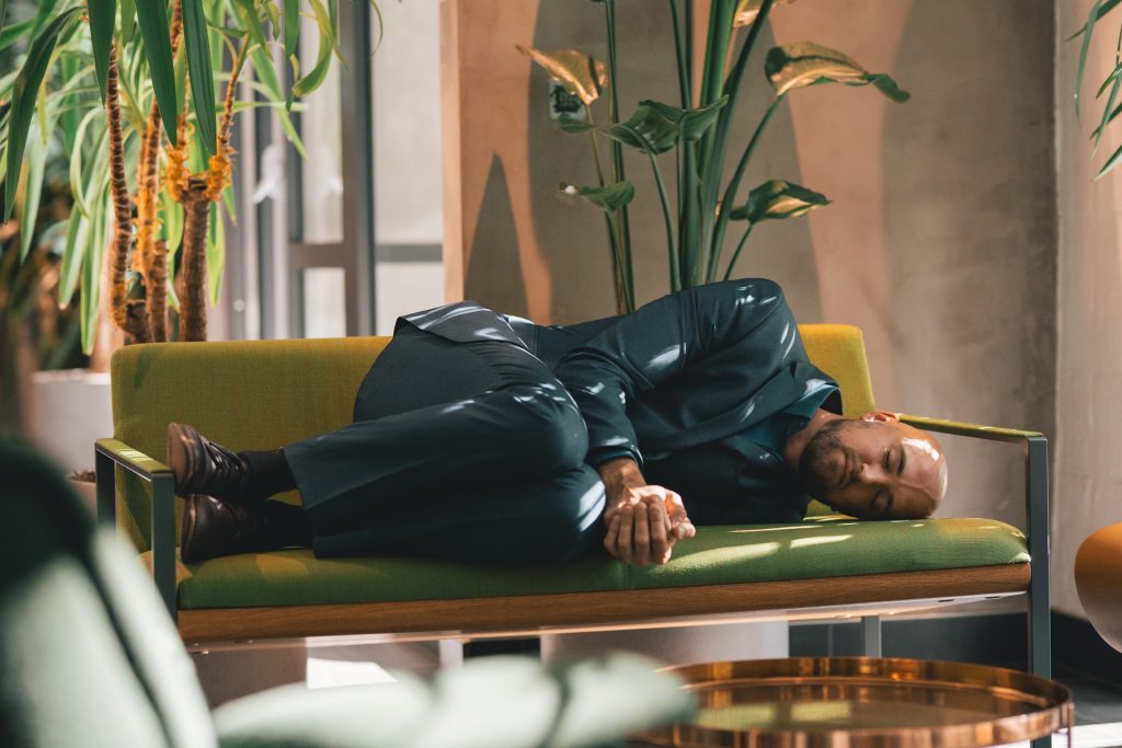 A man power napping on an office couch