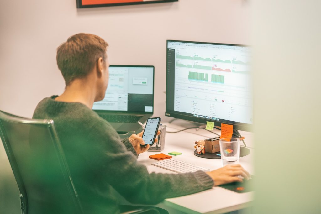 A person using several monitors and a phone for work