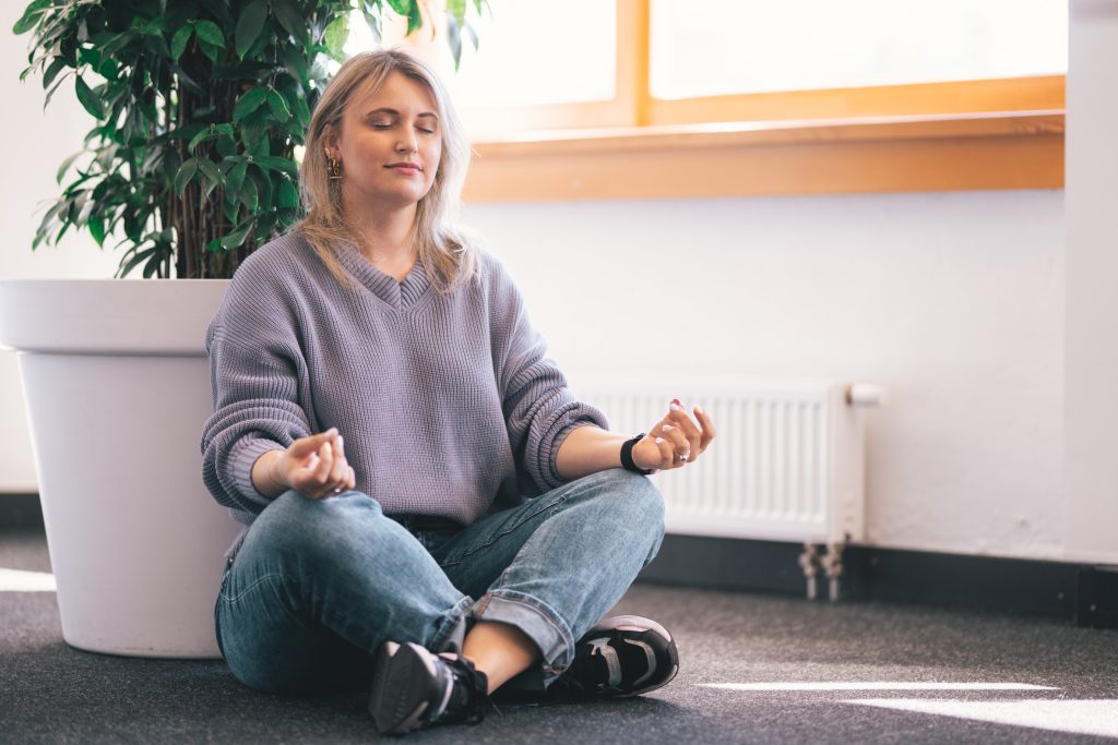 A woman meditating while sitting on a floor