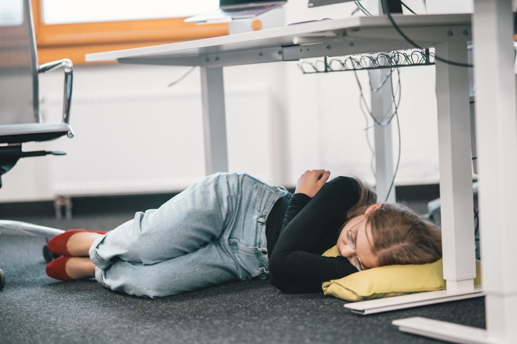 Woman sleeping under office table