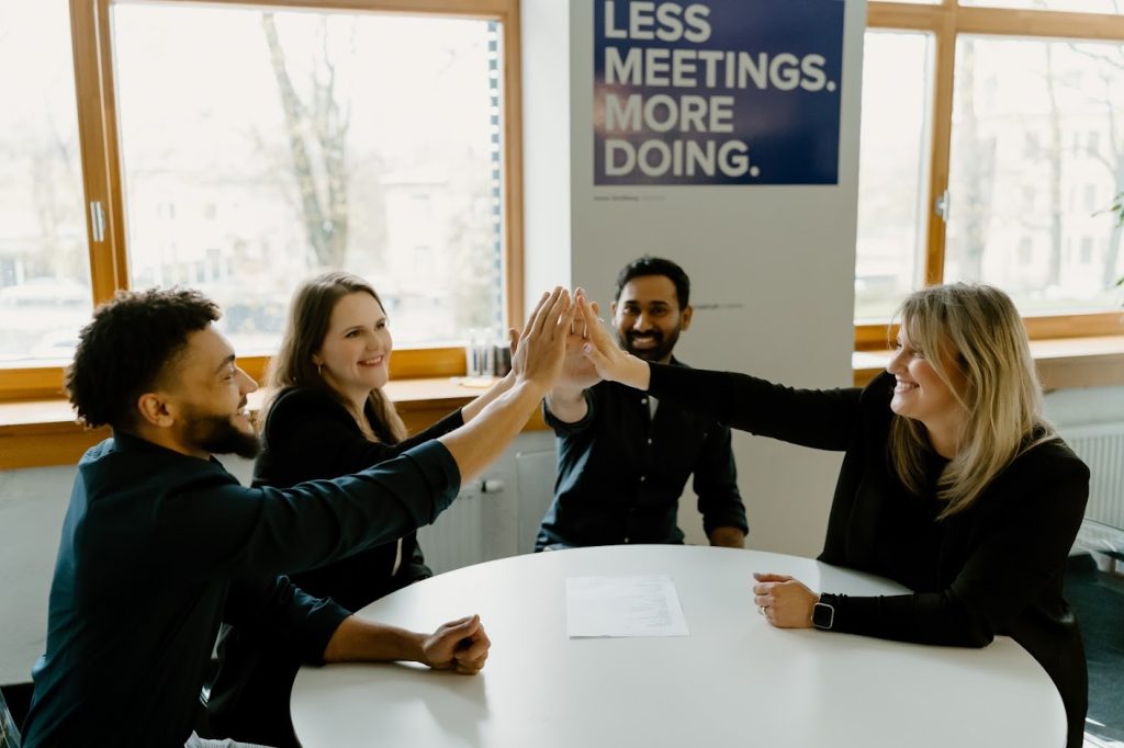 Multicultural team high fiving around circular table