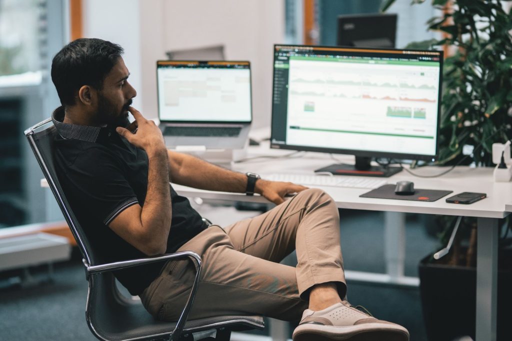 man reclined in front of a computer contemplating how AI is changing the workplace