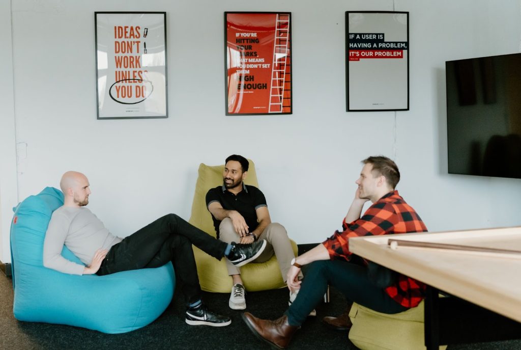 three guys sitting in puffy chairs and talking to each other