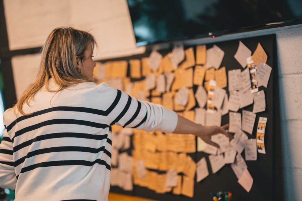 Woman pointing to a specific note on a wall of over a hundred notes