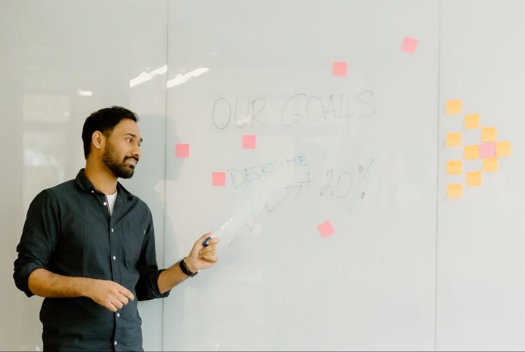 A man explaining whiteboard information, pointing to it