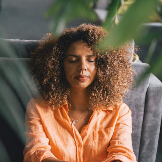 An image of a woman sitting with her eyes closed.